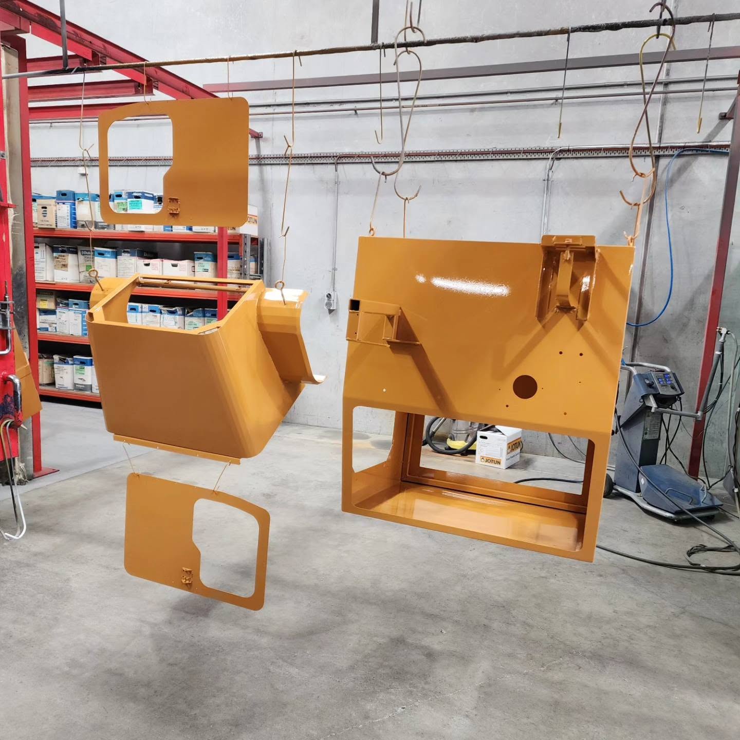 Fresh gold powder-coated metal housings suspended in the 3D Powder Coating workshop