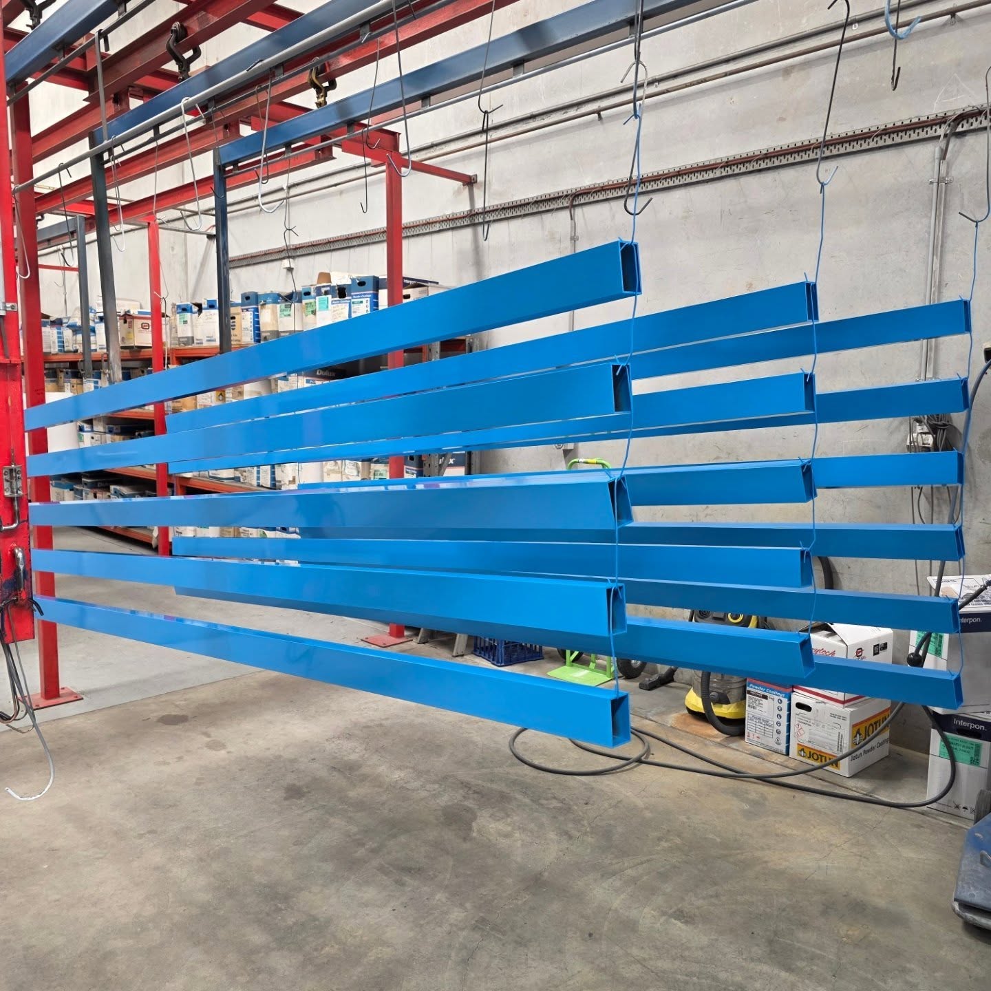 Long architectural metal members finished in bright blue powder coat